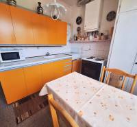 Küche einer 2-Zimmer-Wohnung mit gelben Schränken und Esstisch.