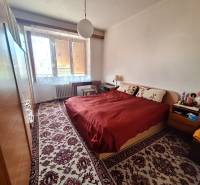 Schlafzimmer in einer 2-Zimmer-Wohnung mit Doppelbett, Teppich, Schränken, Fenster mit Heizkörper.