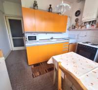 Eine Küche mit einer orangefarbenen Küchenzeile und einem Esstisch in einer Zweizimmerwohnung.