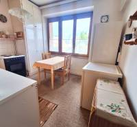 Küche in einer 2-Zimmer-Wohnung mit einem Holzesstisch und einem großen Fenster.