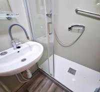Badezimmer in einer 2-Zimmer-Wohnung mit Waschbecken, Duschkabine und Laminatboden.