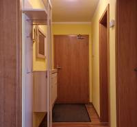 Flur mit Holztüren, gelben Wänden und einem Garderobensystem im Ferienapartment.
