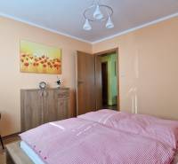 Schlafzimmer in einer Ferienwohnung mit Bett, Kleiderschrank, Sessel und Blumenbild.
