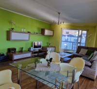 Wohnzimmer mit Kamin in einer Ferienwohnung, grüne Wände, bequeme Sitzgelegenheiten.