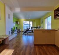 Innenraum einer Ferienwohnung mit Holzboden, Sessel und Küchenzeile in warmen Farben.