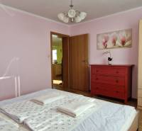 Schlafzimmer im Ferienapartment mit Schrank, roter Kommode und Blumenbild.