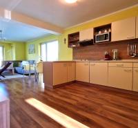 Helle Küche mit Sofa im Ferienapartment, offener Raum mit Holzboden.