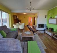 Wohnzimmer in einer Ferienwohnung mit Sofa, Fernseher, Kamin und Kochnische.