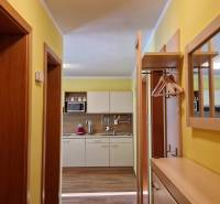 Flur mit Schuhschrank, Spiegel und Blick in die Küche in einer Ferienwohnung.