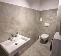 Badezimmer in einer 3-Zimmer-Wohnung mit Waschbecken, Toilette und Waschmaschine, gefliest.