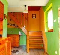Bunte Inneneinrichtung der Hütte mit Treppe und Holzmöbeln.