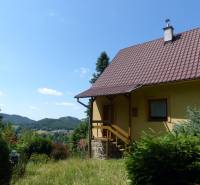 Eine Hütte in Štiavnické Bane, umgeben von Grün und mit Blick auf die Hügel im Hintergrund.