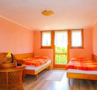 Ein Zweibettzimmer in einer Hütte mit Korbmöbeln und pastellfarbener Wandfarbe.