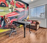 Ein Büro mit einem Ledersessel, einem Tisch und einem künstlerischen Wandgemälde in einer Vierzimmerwohnung.