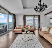 Ein stilvolles Wohnzimmer in einer 4-Zimmer-Wohnung mit einem Sofa, einem Kronleuchter und Blick auf die Terrasse.