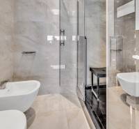 Badezimmer in einer 4-Zimmer-Wohnung mit Duschkabine, Bidet und glänzenden Fliesen.