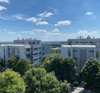 Ein Blick auf moderne Wohnblöcke in Bratislava - Karlova Ves, umgeben von Grün und blauem Himmel.