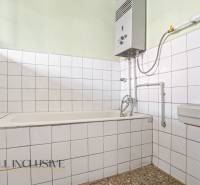 Ein Badezimmer in einem Einfamilienhaus mit weißen Fliesen und einem Gas-Wassererhitzer.