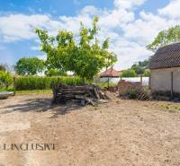 Ein Hof mit einem Holzstapel neben einem Einfamilienhaus in Jahodná, mit blauem Himmel.