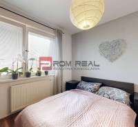 Schlafzimmer in einer 2-Zimmer-Wohnung mit Bett, Lampe und Pflanzen auf der Fensterbank.