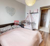 Schlafzimmer mit Kinderbett, rosa Accessoires und Holzboden in einer 2-Zimmer-Wohnung.
