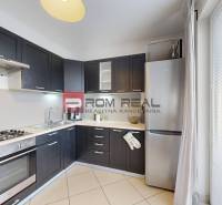 Küche in einer 2-Zimmer-Wohnung mit eingebauten Geräten und dunklen Schränken.