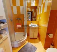 Badezimmer in einer 2-Zimmer-Wohnung mit orangefarbenen Fliesen und einer Duschkabine.