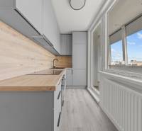 Küche in einer 2-Zimmer-Wohnung mit heller Holzverkleidung und großem Fenster.