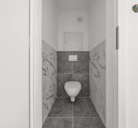 Badezimmer mit Toilette und Marmorfliessen in einer 2-Zimmer-Wohnung.