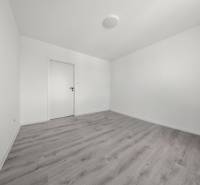 Ein leerer Raum mit weißen Wänden und grauem Boden in einer Zweizimmerwohnung.