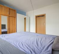 Schlafzimmer in einer 2-Zimmer-Wohnung mit einem Schrank und einem Bett mit grauer Bettwäsche.