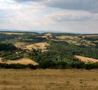 Hügelige Landschaft mit Wäldern und offenen Flächen, ideal für das Wohnen auf dem Land.