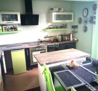 Eine Küche in einem Einfamilienhaus mit grünen und weißen Schränken und einem Esstisch.