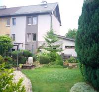 Ein Garten bei einem Einfamilienhaus in Nováky mit Bäumen und einem Kiesweg.