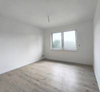 Innenraum eines Zimmers in einem Einfamilienhaus mit weißen Wänden und hellem Holzboden.