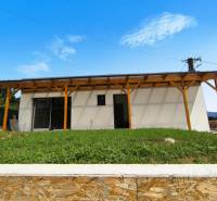 Ein Einfamilienhaus in Malé Kršteňany mit einer Holzpergola und einem Rasen am Hang.