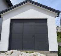 Ein Einfamilienhaus in Malé Krštenany mit einer weißen Garage und dunklen Türen.