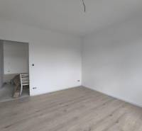 Ein leerer Raum mit weißen Wänden und hellem Holzboden in einem Einfamilienhaus.