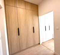 Ein Studio-Apartment mit eingebauten Holzschränken und weißen Wänden wirkt gemütlich.