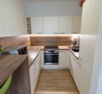 Küche in einer 3-Zimmer-Wohnung mit hellen Möbeln und einer Arbeitsplatte aus Holz.