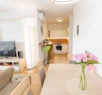 Wohnzimmer und Küche in einer 3-Zimmer-Wohnung, mit Holzmöbeln und dekorativen Blumen.