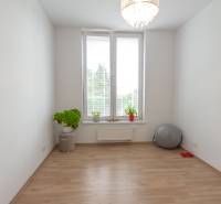 Ein geräumiges Zimmer in einer 3-Zimmer-Wohnung, helle Wände, Blumen und Fitnesszubehör.