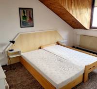 Doppelbett unter einer schrägen Decke in einer Zweizimmerwohnung mit einem Bild an der Wand.