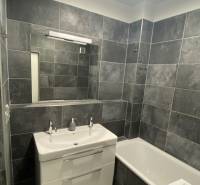 Badezimmer mit grauen Fliesen und weißer Sanitäreinrichtung in einer 4-Zimmer-Wohnung.