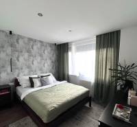 Schlafzimmer in einer 4-Zimmer-Wohnung mit einem bequemen Bett, einer Pflanze und Möbeln.