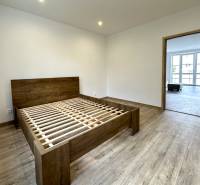 Schlafzimmer in einer 2-Zimmer-Wohnung mit Holzboden und einem Bett ohne Matratze.