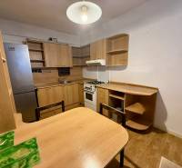 Küche in einer Einzimmerwohnung ausgestattet mit Holzmöbeln und einem Kühlschrank.