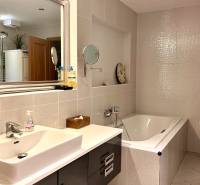 Das Badezimmer in der 3-Zimmer-Wohnung enthält eine Badewanne, ein Waschbecken und Aufbewahrungsschränke.