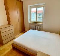 Ein Schlafzimmer mit Holzmöbeln, einem großen Bett und einem Fenster in einer 2-Zimmer-Wohnung.