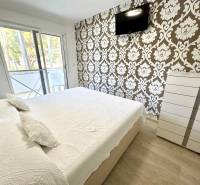 Schlafzimmer in einer 4-Zimmer-Wohnung mit einem Fernseher an der Wand, gemusterte Tapete, Schiebetüren.